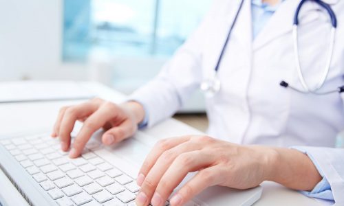 Close-up of a medical worker typing on laptop